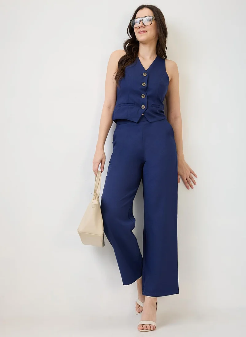 جلو باص طقم نسائي بلون كحلي من جلوبس، سترة بياقة على شكل حرف  وجيوب أمامية مع بنطلون، طقم عمل